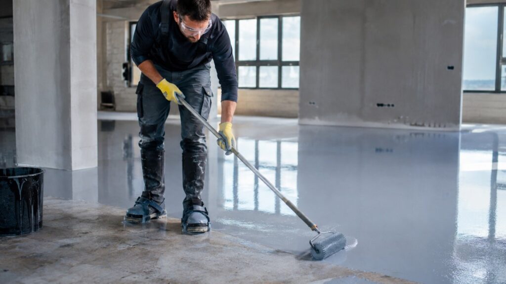 Contractor installing self-levelling epoxy flooring for home India project